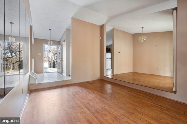 spare room with lofted ceiling, hardwood / wood-style floors, and a chandelier