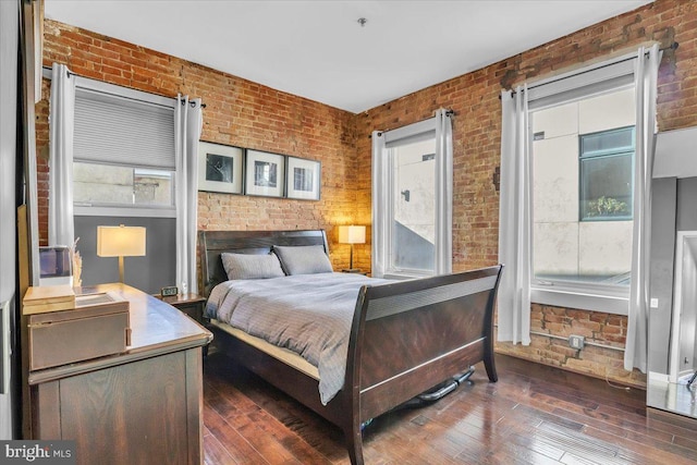 bedroom with brick wall and dark hardwood / wood-style flooring