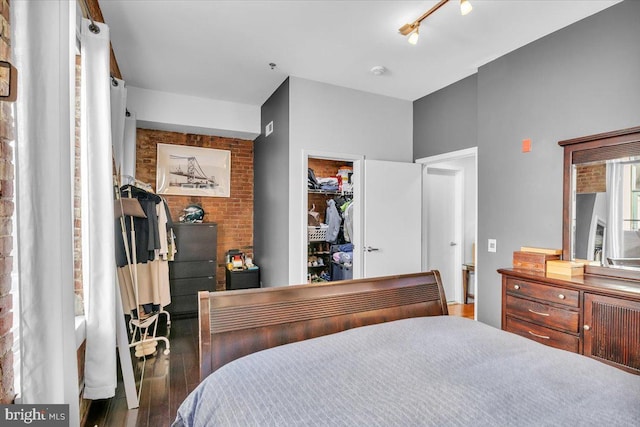 bedroom with a closet, a spacious closet, wood-type flooring, and rail lighting