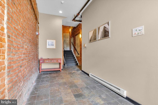 corridor featuring brick wall and baseboard heating