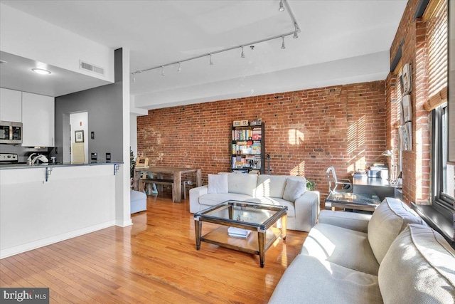 living room with brick wall and light hardwood / wood-style flooring