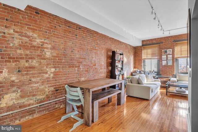 living room featuring brick wall, track lighting, and light hardwood / wood-style flooring