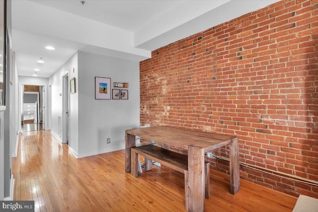 dining room with light hardwood / wood-style floors and brick wall