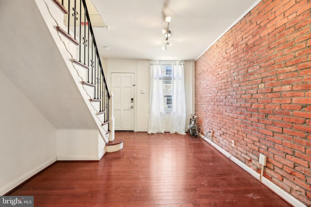 entryway with hardwood / wood-style floors, rail lighting, and brick wall