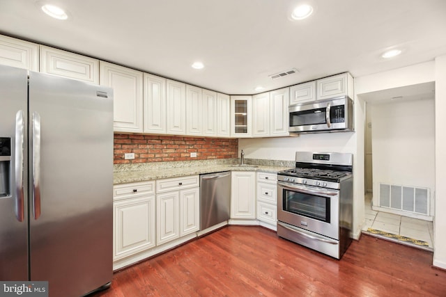 kitchen featuring sink, light stone counters, dark hardwood / wood-style floors, stainless steel appliances, and white cabinets