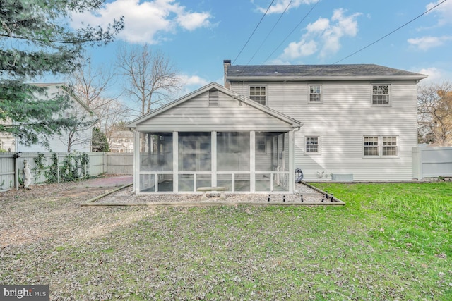 back of property featuring a sunroom and a lawn