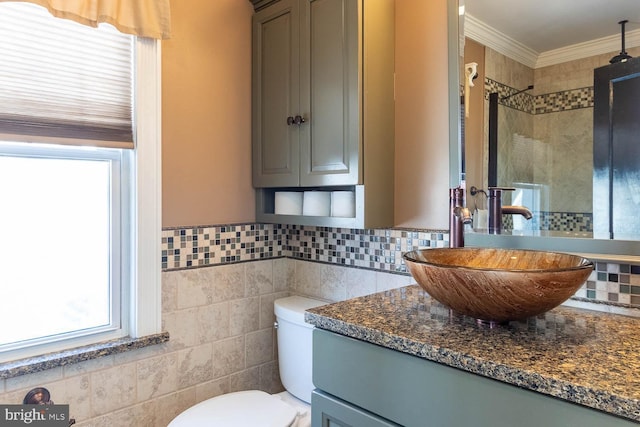 bathroom with tile walls, vanity, a tile shower, ornamental molding, and toilet