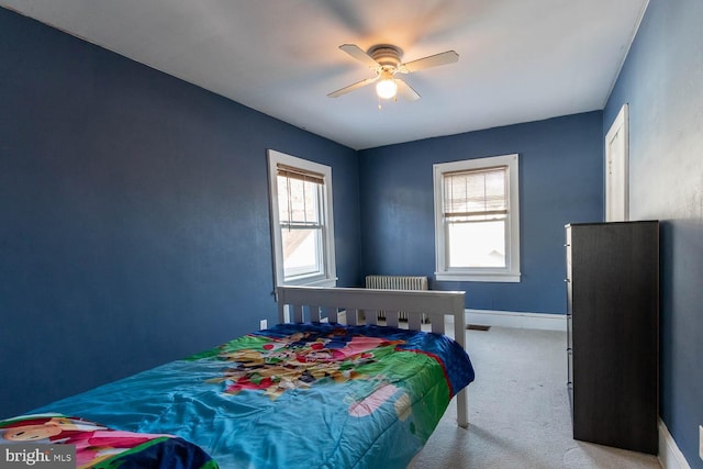 bedroom featuring multiple windows, light carpet, radiator heating unit, and ceiling fan