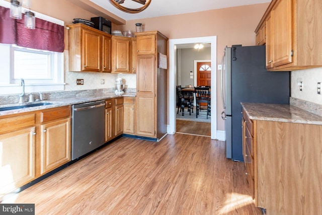 kitchen featuring appliances with stainless steel finishes, tasteful backsplash, sink, light stone counters, and light hardwood / wood-style floors