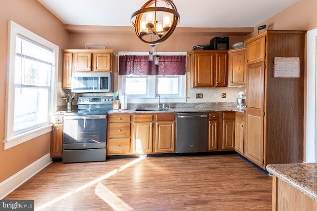 kitchen with hardwood / wood-style flooring, appliances with stainless steel finishes, sink, and pendant lighting