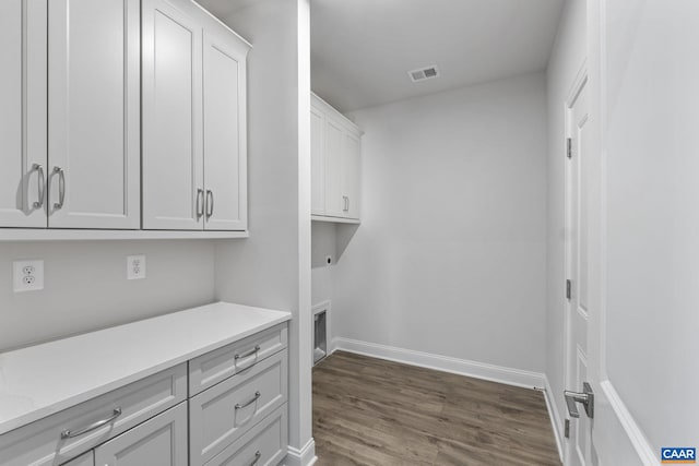 clothes washing area featuring cabinets, electric dryer hookup, and dark hardwood / wood-style flooring