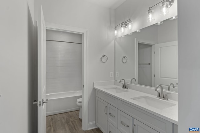 full bathroom featuring hardwood / wood-style flooring, washtub / shower combination, vanity, and toilet