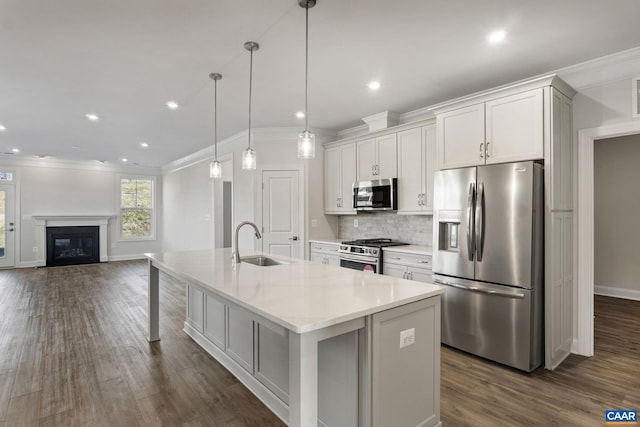 kitchen featuring decorative light fixtures, sink, white cabinets, a kitchen island with sink, and stainless steel appliances