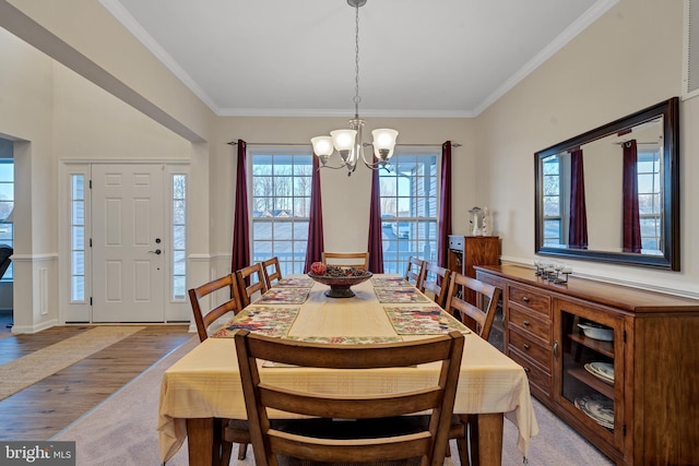 dining area with an inviting chandelier, crown molding, and light hardwood / wood-style floors