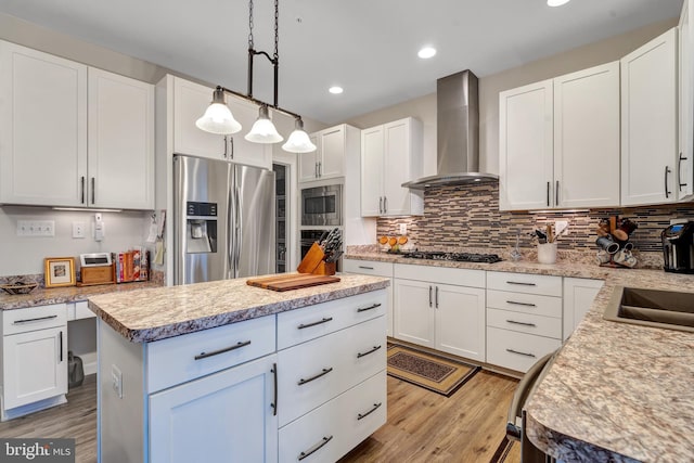 kitchen with a kitchen island, white cabinetry, appliances with stainless steel finishes, and wall chimney exhaust hood