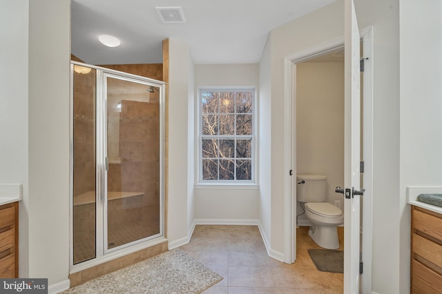 bathroom featuring vanity, a shower with door, tile patterned floors, and toilet