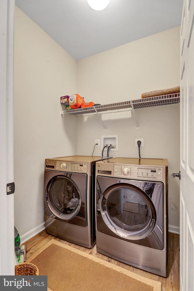 laundry room featuring separate washer and dryer, hardwood / wood-style floors, and a wood stove