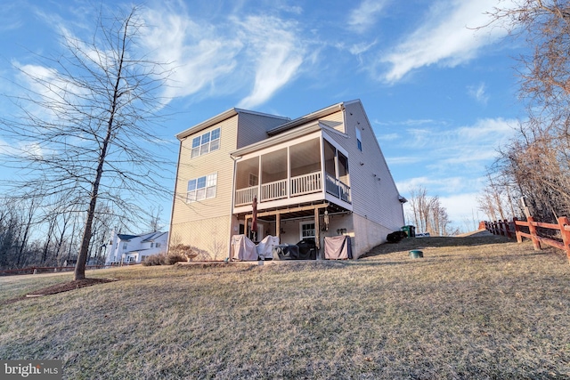 rear view of house featuring a lawn and a sunroom