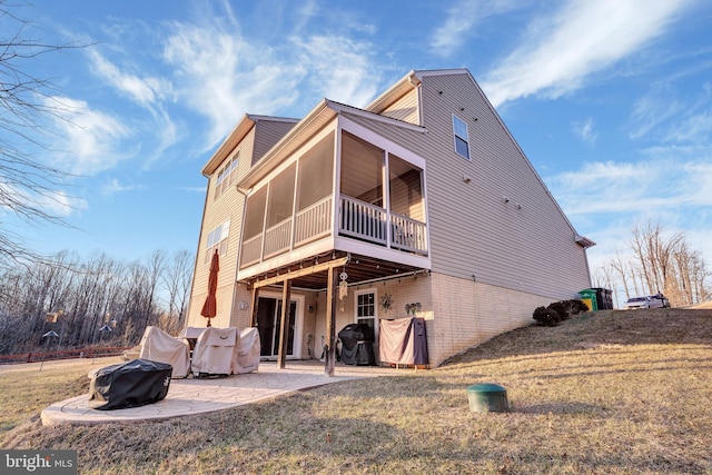 rear view of house featuring a patio area, a sunroom, and a lawn