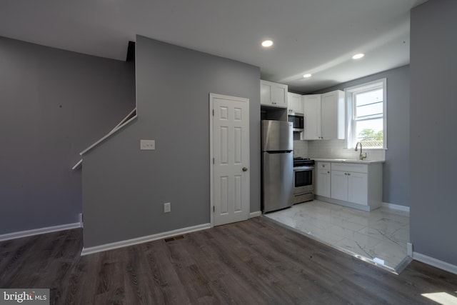 kitchen featuring appliances with stainless steel finishes, tasteful backsplash, white cabinetry, sink, and dark wood-type flooring