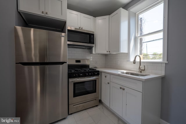 kitchen with stainless steel appliances, tasteful backsplash, sink, and white cabinets