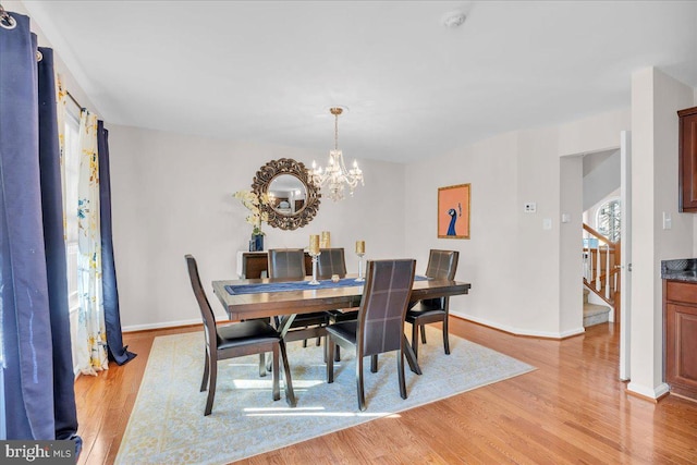 dining area with light hardwood / wood-style flooring and a chandelier