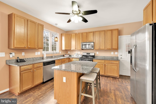 kitchen featuring appliances with stainless steel finishes, sink, a kitchen breakfast bar, a center island, and light stone counters