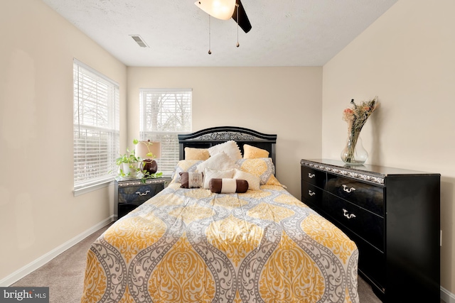 carpeted bedroom with ceiling fan and a textured ceiling