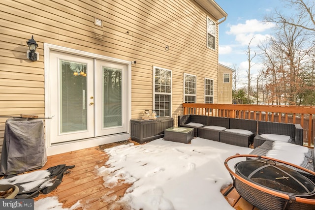 snow covered deck featuring an outdoor living space with a fire pit and french doors