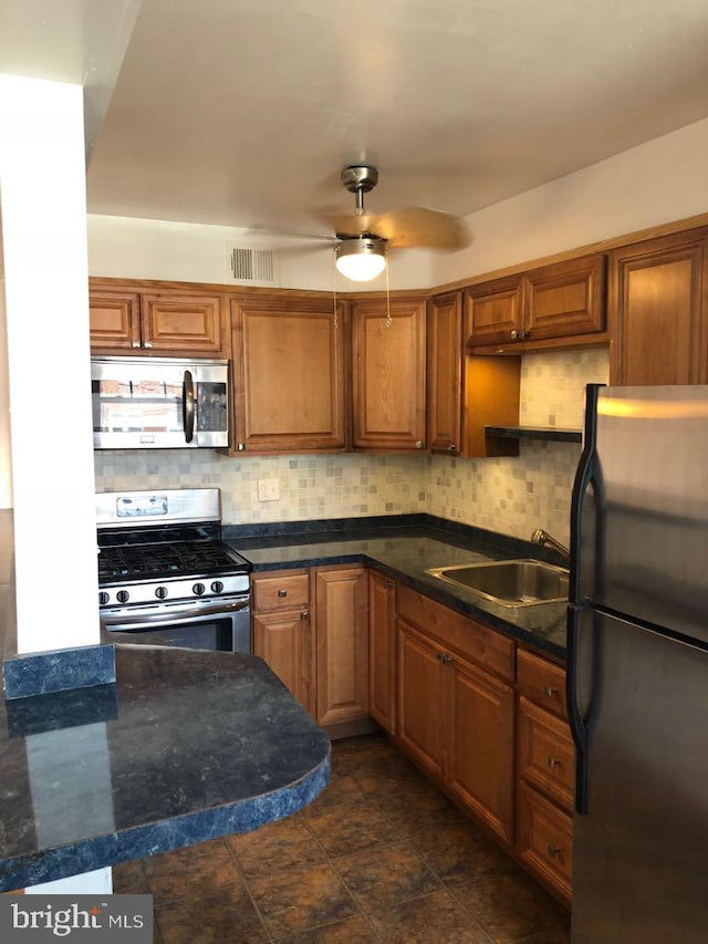 kitchen featuring ceiling fan, appliances with stainless steel finishes, sink, and decorative backsplash