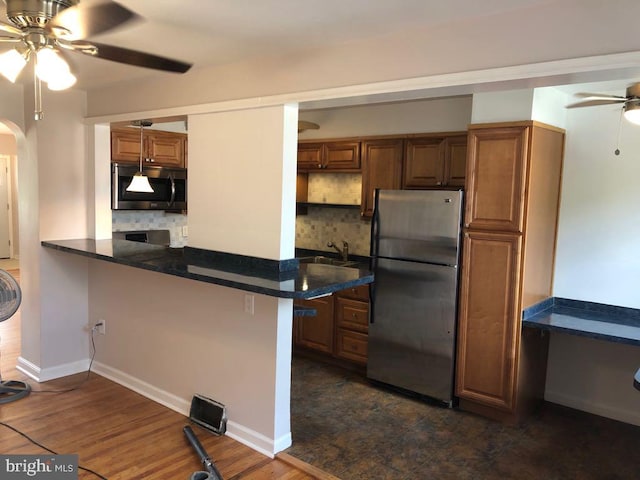 kitchen featuring ceiling fan, stainless steel appliances, kitchen peninsula, and decorative backsplash