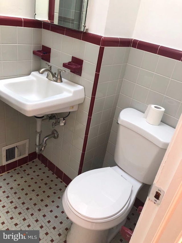 bathroom featuring toilet and tile walls