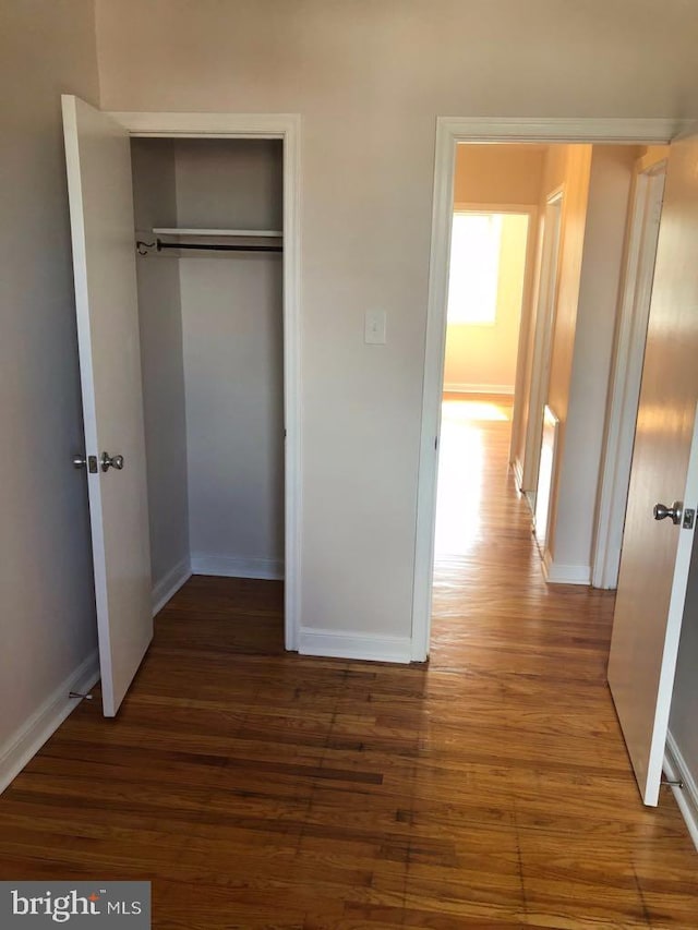 unfurnished bedroom featuring dark hardwood / wood-style flooring and a closet