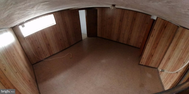 bonus room with wooden walls and vaulted ceiling