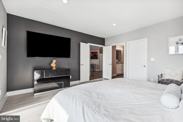 bedroom featuring ensuite bathroom and light wood-type flooring