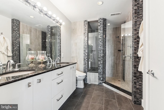 bathroom featuring vanity, a tile shower, tile patterned floors, and toilet