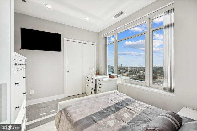 bedroom with light hardwood / wood-style floors and a closet