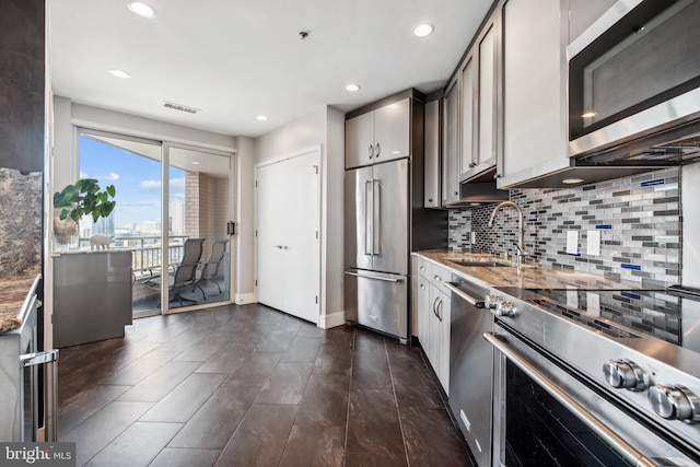 kitchen featuring stainless steel appliances, sink, stone counters, and decorative backsplash