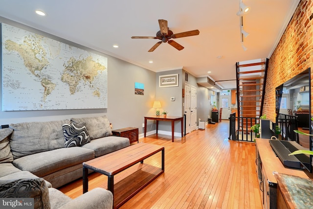 living room featuring ceiling fan, ornamental molding, brick wall, and light hardwood / wood-style floors