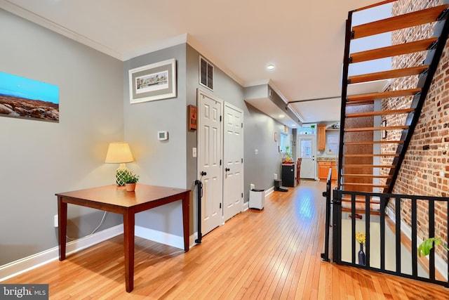 corridor featuring ornamental molding and light hardwood / wood-style flooring