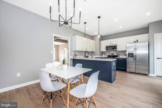 kitchen featuring appliances with stainless steel finishes, white cabinetry, hanging light fixtures, blue cabinets, and kitchen peninsula