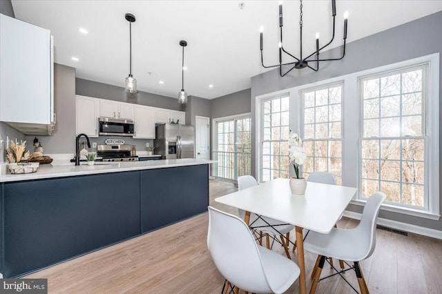 dining space featuring sink, light hardwood / wood-style flooring, and a notable chandelier