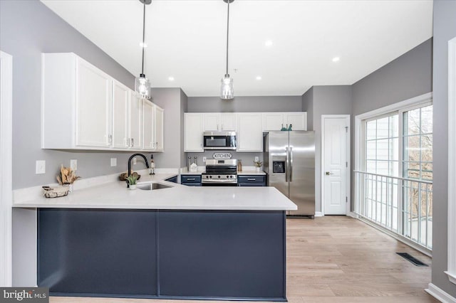 kitchen featuring sink, hanging light fixtures, white cabinets, and appliances with stainless steel finishes