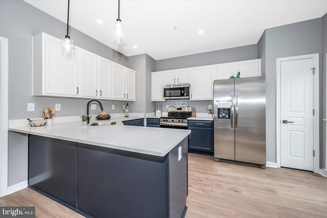 kitchen featuring pendant lighting, stainless steel appliances, kitchen peninsula, and sink