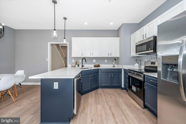 kitchen featuring sink, appliances with stainless steel finishes, blue cabinets, decorative light fixtures, and kitchen peninsula