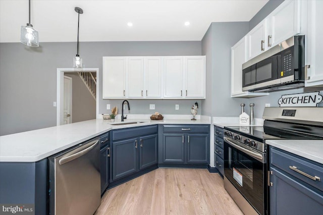 kitchen featuring sink, blue cabinetry, white cabinetry, hanging light fixtures, and stainless steel appliances