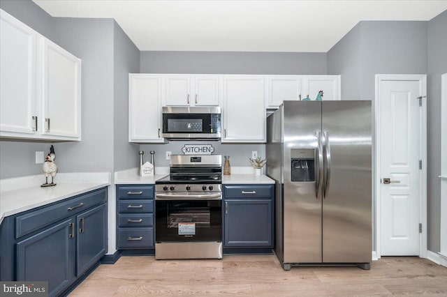 kitchen with blue cabinets, white cabinetry, and appliances with stainless steel finishes