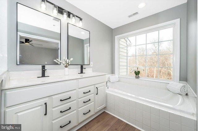 bathroom featuring vanity, hardwood / wood-style floors, and a relaxing tiled tub