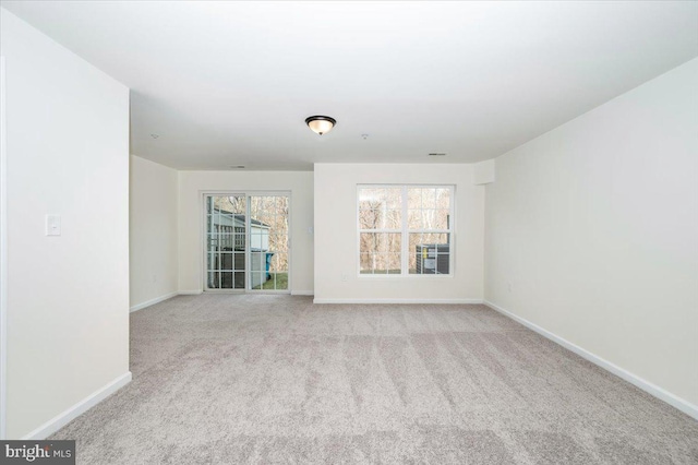 empty room featuring a wealth of natural light and light colored carpet