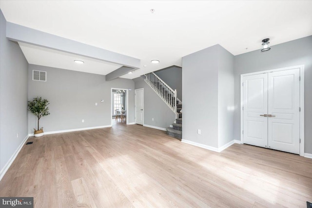 unfurnished living room featuring beamed ceiling and light wood-type flooring